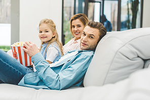 side view of family with popcorn  while watching film together at home