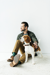 handsome man sitting with cute beagle on carpet