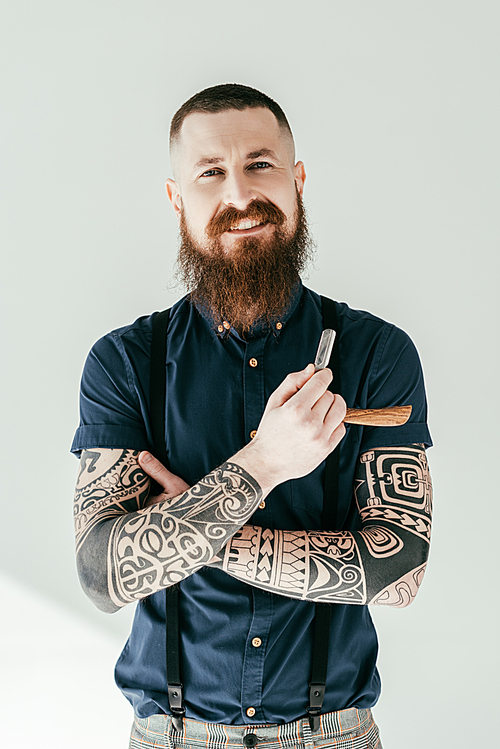smiling tattooed man holding razor and  isolated on white