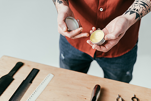 cropped image of tattooed barber holding wax isolated on white