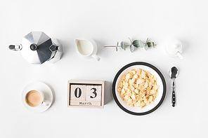flat lay with corn flakes in bowl for breakfast, coffee maker and calendar on white surface