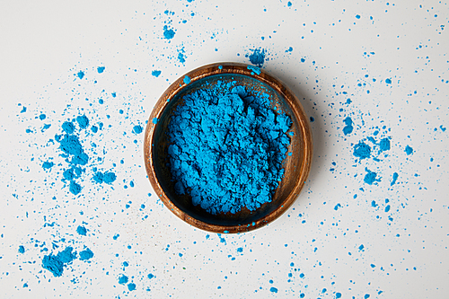 top view of blue holi paint in bowl isolated on white, Hindu spring festival