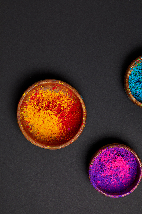 top view of colorful holi powder in bowls on grey surface, Hindu spring festival