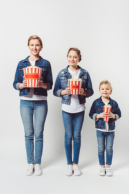 smiling family in similar denim clothing with popcorn isolated on grey