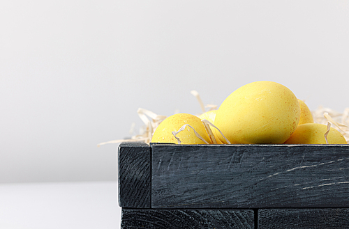 yellow painted easter eggs in wooden box on white