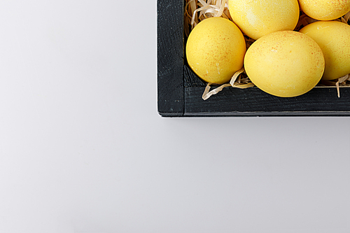 top view of yellow painted easter eggs in wooden box isolated on white