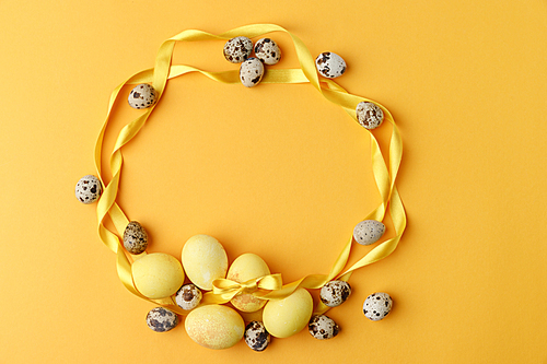 top view of yellow painted easter eggs and quail eggs on yellow