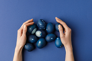 cropped image of woman touching blue painted easter eggs