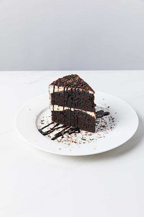 Front view of chocolate cake with glaze on plate placed on white surface