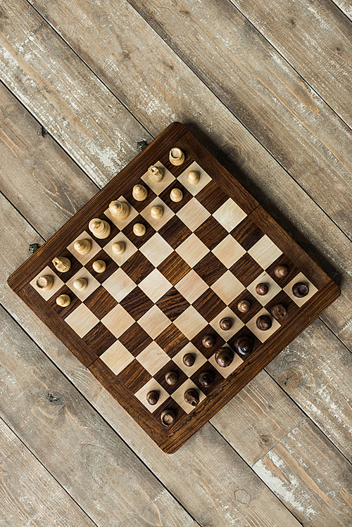Top view of chess board with chess pieces set for new game on wooden surface