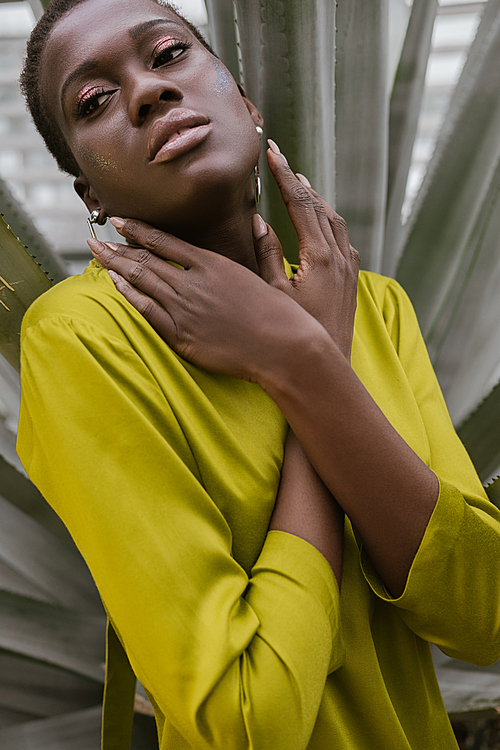 stylish beautiful african american woman with glitter makeup posing in yellow dress