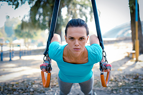 Active woman in sportswear doing exercises in outdoor gym in the park
