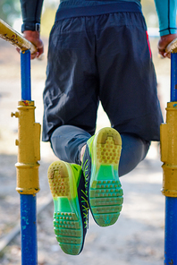 Back view of muscular man on parallel bars during exercising in a park