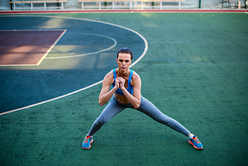 Muscular woman in sportswear doing exercises on stadium