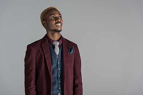 smiling african american in jacket looking upwards isolated on grey