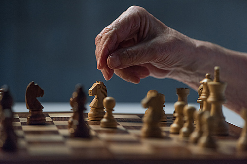 Close-up view of senior man playing chess board game