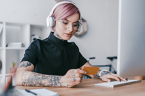 유토이미지 | young businesswoman in headphones holding credit card and using ...