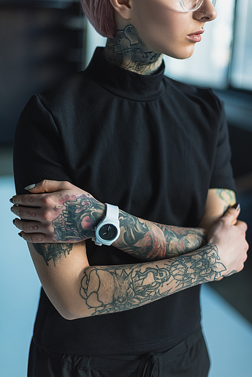 cropped shot of young tattooed businesswoman standing with crossed arms