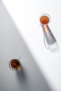 top view of two glass cups with tea on table with shadow