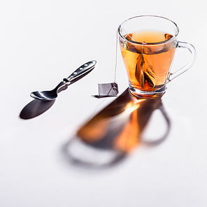 glass cup of black tea and spoon on table