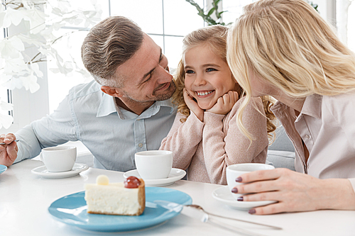 parents and their adorable little daughter spending time at cafe