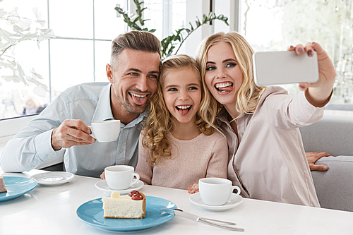 happy young family taking selfie with tongues out at restaurant