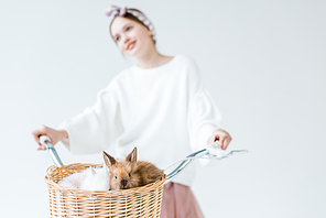 close-up view of teenage girl riding bicycle with cute furry rabbits in basket