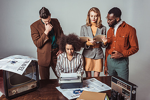 multicultural retro styled journalists at newsroom on grey