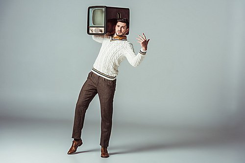 retro styled handsome man posing with vintage television on shoulder