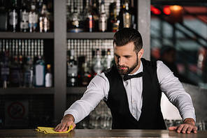 handsome bartender cleaning bar counter in evening