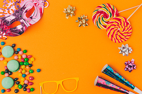flat lay with candies and and party objects isolated on orange, purim holiday concept