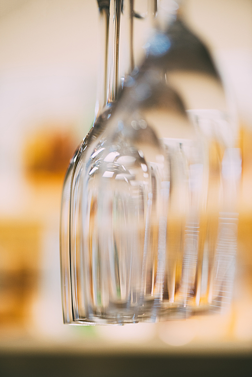 close-up view of clean empty wine glasses hanging in bar