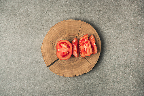 top view of cuted tomato on wooden stump on grey concrete tabletop