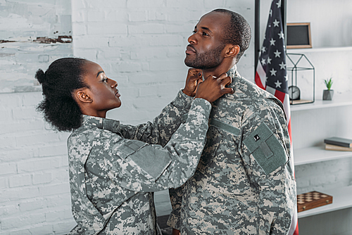 African american woman helping man to get dressed in camouflage clothes