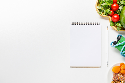 top view of blank notebook near diet food and skipping rope on white background
