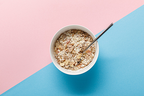top view of breakfast cereal in bowl on blue and pink background