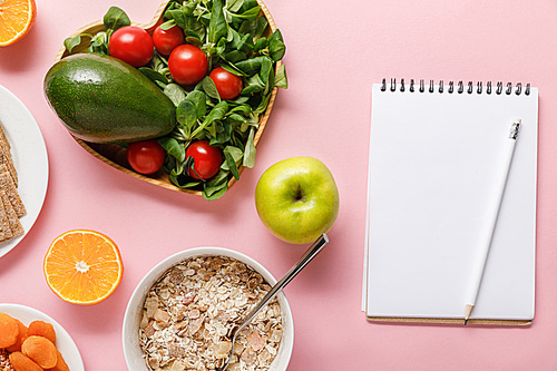 top view of fresh diet food and blank notebook on pink background