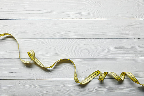 top view yellow measuring tape on wooden white background with copy space