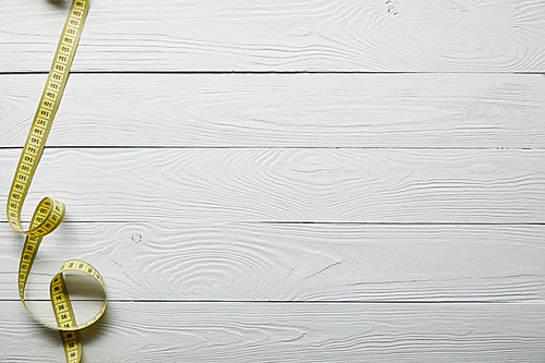 top view yellow measuring tape on wooden white surface with copy space