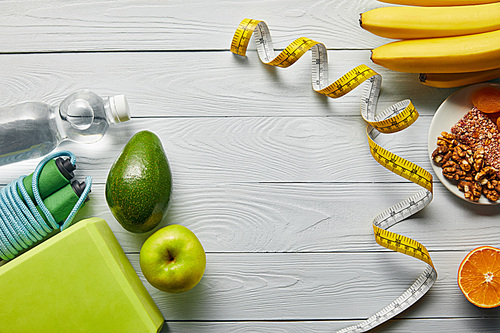 top view of diet food near measuring tape and sport equipment on wooden white table with copy space
