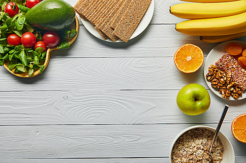 top view of fresh fruits, vegetables and cereal on wooden white background with copy space