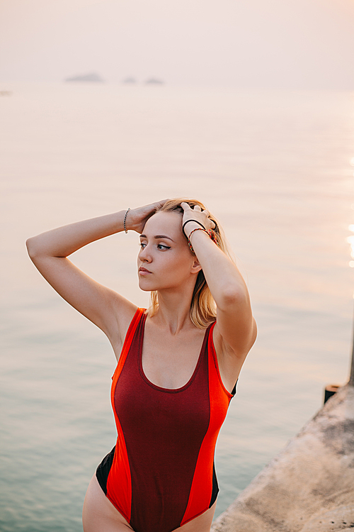 beautiful girl posing in swimsuit near ocean and looking away