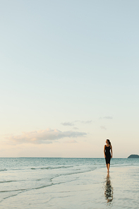 attractive woman walking on ocean beach during