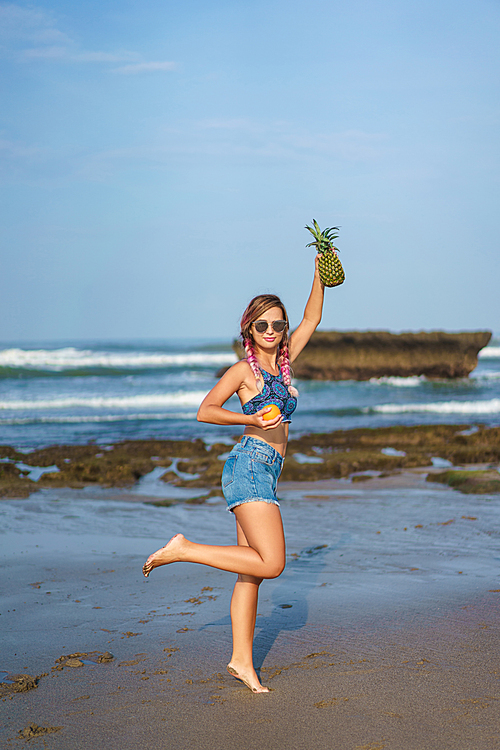 attractive young woman with orange and pineapple on beach