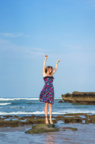 happy young woman in dress jumping on beach