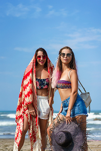 happy young women in bikini and sunglasses on beach