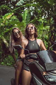 beautiful young women riding motorcycle and smiling at camera in jungles