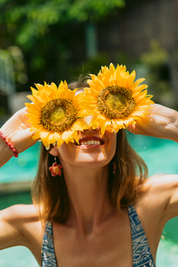 beautiful smiling woman in bikini holding sunflowers at sunny day