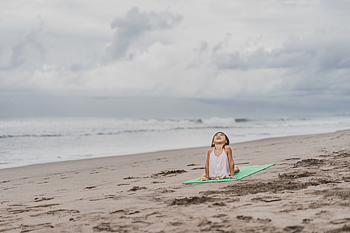 happy little child practicing yoga in Upward-Facing Dog (Urdhva Mukha Svanasana) pose on seashore
