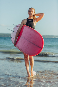beautiful female surfer with surfboard on beach